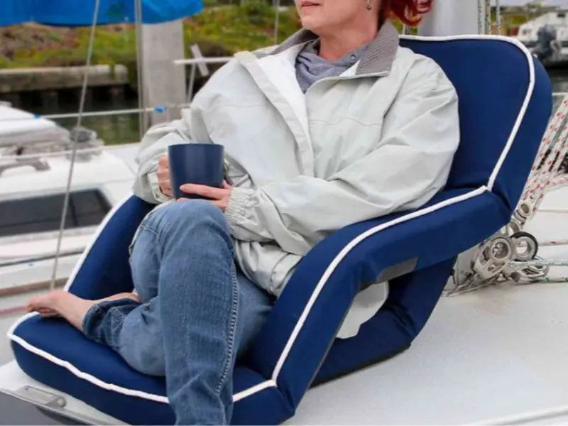 Woman sitting on portable seat and drinking coffee on a sailboat 
